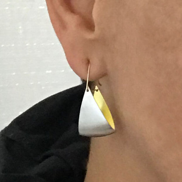 close up of silver and gold fan earrings on woman