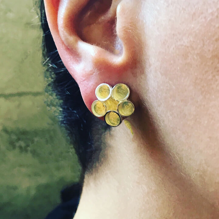 close up of gold daisy earring on face