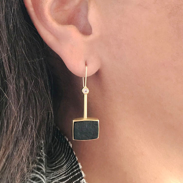 close up of gold black onyx earrings on woman